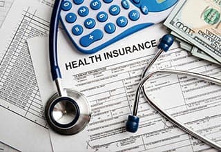 health insurance paperwork with stethescope and calculator